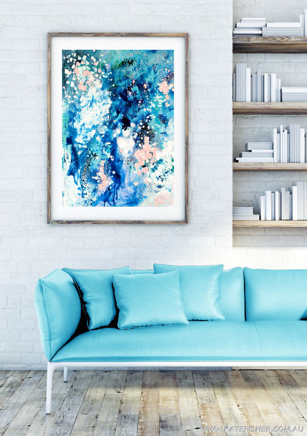 "When Snow Falls" abstract wall art print in blues and blush by Australian artist Kate Fisher styled in modern white living room interior with blue couch.